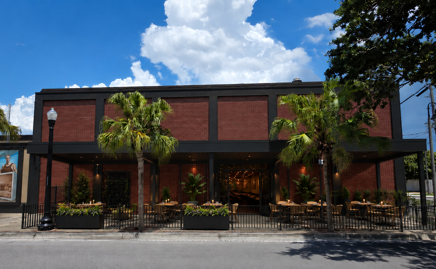 Daytime concept rendering of the Bank Street patio side of Signal House with outdoor tables, planting, black railings, and open restaurant doors.