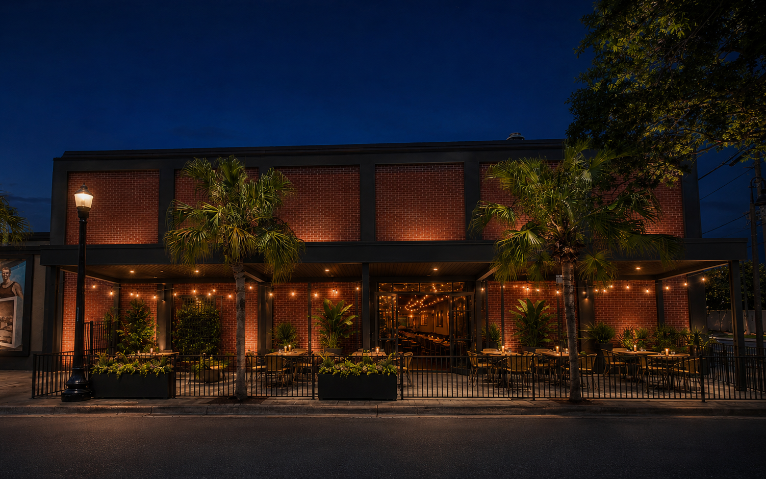 Night concept rendering of the Bank Street patio side of Signal House with outdoor dining, warm lighting, palms, and open restaurant doors.